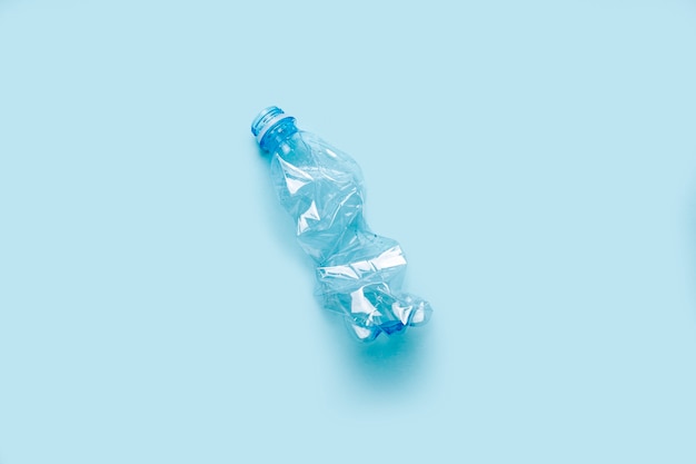 Gebrauchte Plastikflasche auf blauem Hintergrund. Das Konzept der Verwendung von Kunststoff. Umweltproblem, globale Umwelt. Ansicht von oben, flach.