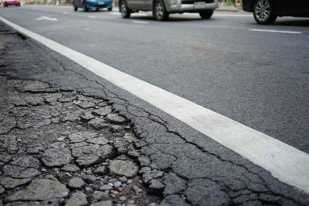 Gebrochene Oberfläche auf der Straße mit Autos auf Hintergrund