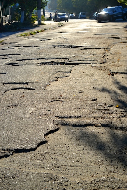 Gebrochene Straße in den Gruben auf der Straße morgens bei Sonnenschein