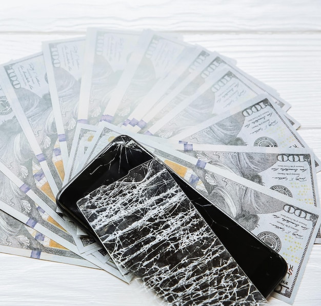 Gebrochener Bildschirmschutz aus gehärtetem Glas Geld, das in der Nähe des Telefons liegt Dollarnoten