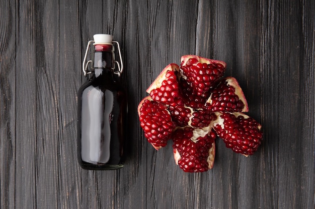 Gebrochener Granatapfel und Granatapfelsaft in einer Flasche auf einer Draufsicht des dunklen Hintergrundes