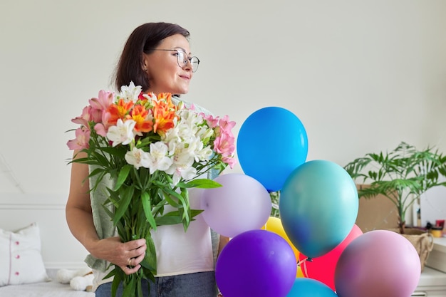 Geburtstag 45 Jahre alte glückliche Frau mit Blumenstrauß und Luftballons