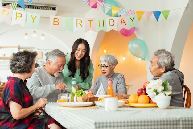 Geburtstagsfeier in der Senioren-Kindertagesstätte der asiatischen Ältesten, männlichen, weiblichen, Lachen, Lächeln, positiven Gesprächsgrüße, Geburtstagsparty mit Freunden in der Senioren-Kindertagesstätte des Pflegeheims Älterer männlicher Geburtstag