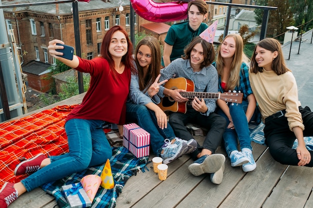 Foto geburtstagsgruppen-selfie auf einem dach. freunde, die fotos machen, um sie in sozialen netzwerken zu teilen. jugend-bff-lifestyle