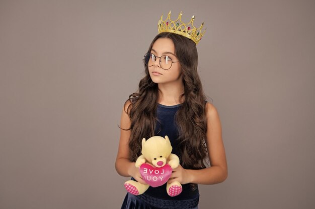 Foto geburtstagsparty für kinder porträt eines ehrgeizigen teenagermädchens mit krone, das sich als prinzessin fühlt, selbstvertrauen, krone des kindesprinzessens auf einem isolierten studio-hintergrund