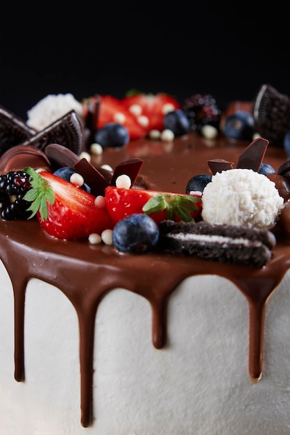 Geburtstagstorte auf dunklem Hintergrund Nahaufnahme von Kuchen mit frischen Beeren und Schokoladenbonbons