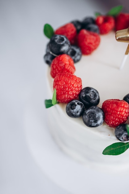 Foto geburtstagstorte mit beeren, himbeere und heidelbeerkinderhände