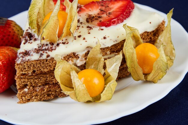 Geburtstagstorte mit Erdbeeren und Physalis auf einer weißen Platte