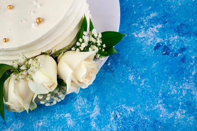 Geburtstagstorte mit weißen Rosen auf blauem Hintergrund.