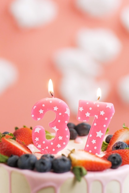 Geburtstagstorte Nummer 37 Schöne rosa Kerze im Kuchen auf rosa Hintergrund mit weißen Wolken Closeup und vertikale Ansicht