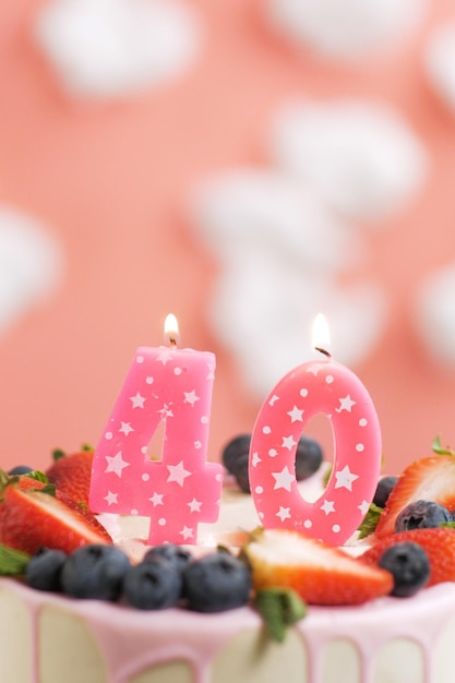 Foto geburtstagstorte nummer 40 schöne rosa kerze im kuchen auf rosa hintergrund mit weißen wolken closeup und vertikale ansicht