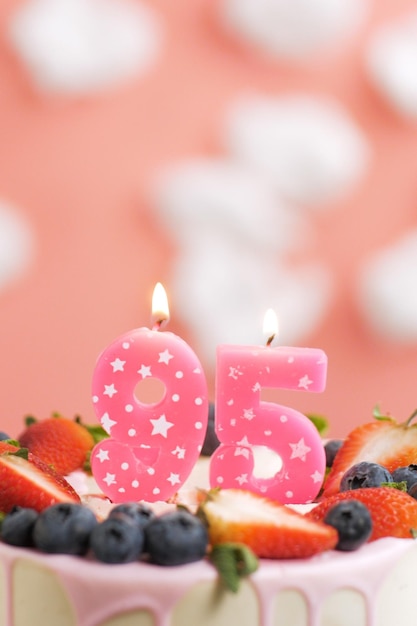 Foto geburtstagstorte nummer 95 schöne rosa kerze im kuchen auf rosa hintergrund mit weißen wolken closeup und vertikale ansicht