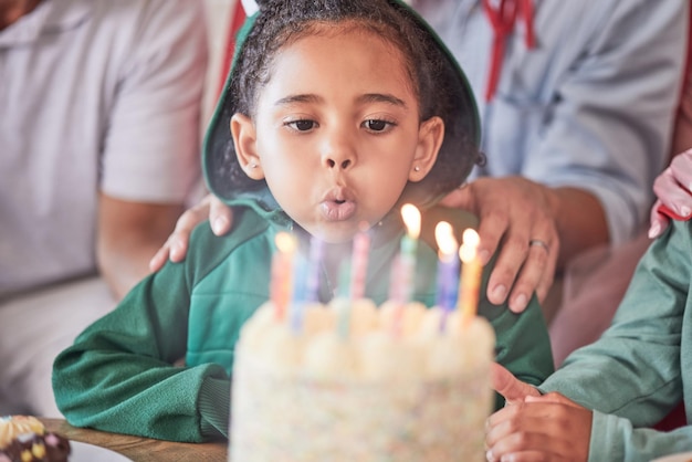 Geburtstagstorte und Mädchen mit Kerzen glücklich und aufgeregt bei einer Partyfeier mit Familie Kinderveranstaltung und Geburtstagsfeierspaß durch Kinderblasen und Geburtstagstortenkerze und ihren besonderen Tag genießen