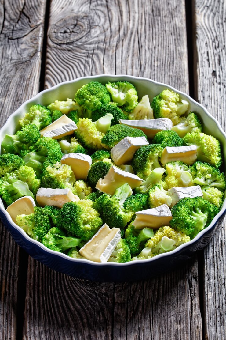 Foto gedämpfte brokkoliröschen zum backen mit brie-käse in einer auflaufform, vertikale ansicht