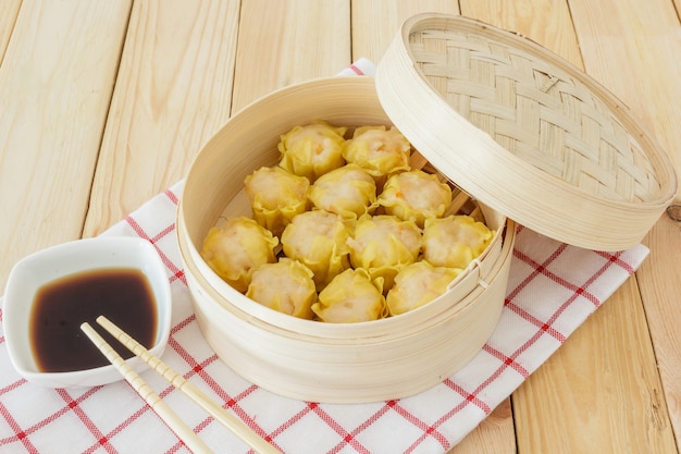 Gedämpfte Mehlklöße (chinesisches dim sum) im Bambuskorb auf Holztischhintergrund