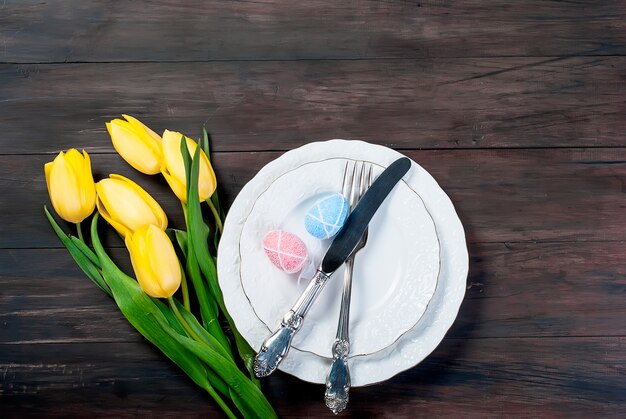 Gedeck für Ostern auf einem hölzernen Hintergrund