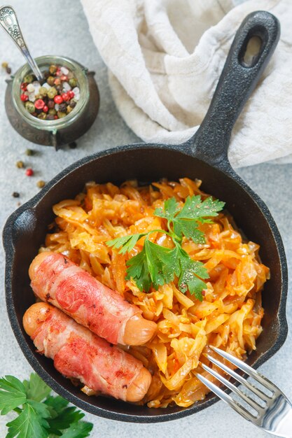 Gedünsteter Kohl mit Karotten, Zwiebeln und Tomaten und Würstchen im Speckmantel mit Petersilie und Gewürzen