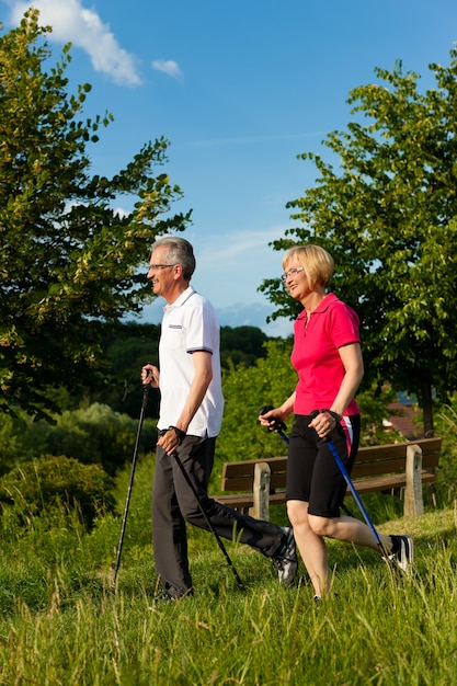 Foto geeignete ältere paare mit den nordic-walking-stöcken, die ihre wanderung in der natur genießen