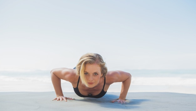 Geeignete Blondine in Plankenposition am Strand