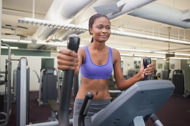 Geeignete Frau, die auf dem Cross-Trainer ausarbeitet