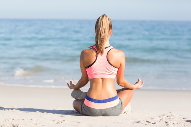 Geeignete Frau, die Yoga neben dem Meer tut