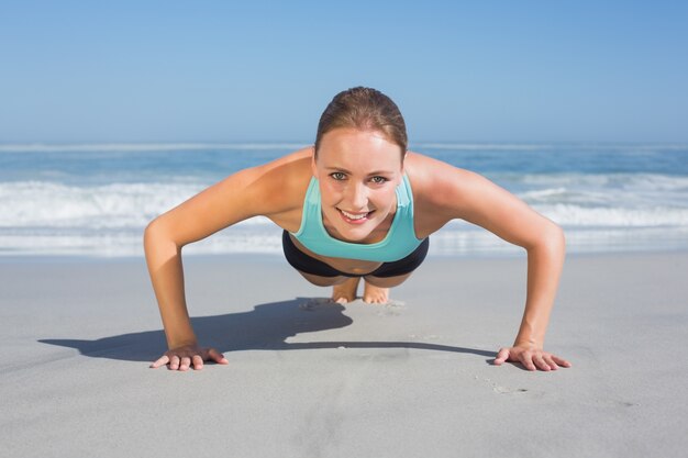 Geeignete Frau in Plankenposition am Strand