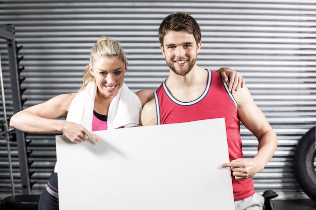 Geeignete Paare, die leeres Papier an crossfit Turnhalle halten