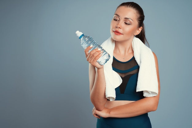 Geeignete sportliche Frau, die Mineralwasserflasche in ihrer Hand hält