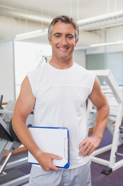 Geeigneter persönlicher Trainer, der an der Kamera im Eignungsstudio lächelt