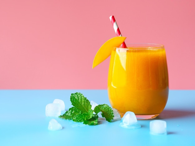 Geeiste Mango-Smoothies auf rosa und blauem Hintergrund für Sommerparty-Getränkekonzept