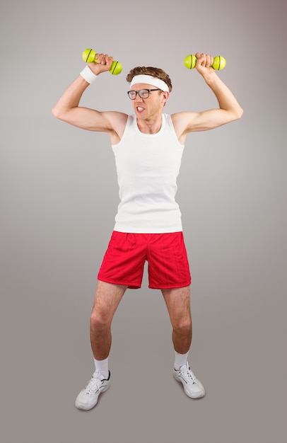 Geek hipster posando en ropa deportiva con pesas