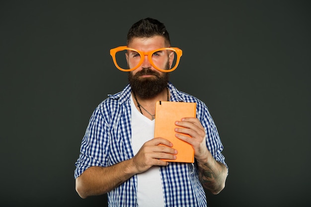 Geek ist schick Studieren Sie Nerd, der Buch hält Männlicher Student der Universität mit Vorlesungsnotizen Buchen Sie Nerd, der ausgefallene Gläser trägt Bärtiger Mann in der Partybrille mit Unterrichtsbuch