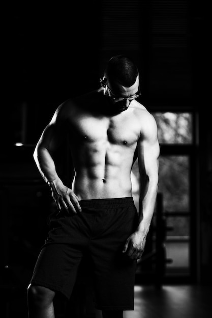 Geek muscular hombre flexionando los músculos en el gimnasio