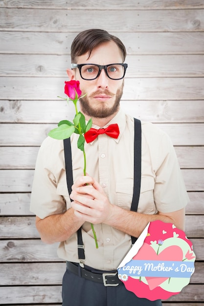 Geekiger Hipster, der eine Rose gegen Holzplanken anbietet
