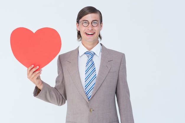 Geeky empresario sonriendo y sosteniendo la tarjeta de corazón