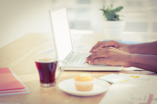 Geerntete Hände, die an Laptop am Schreibtisch arbeiten