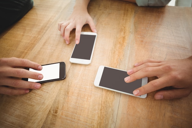 Geerntete Hände, die Smartphones im Büro berühren