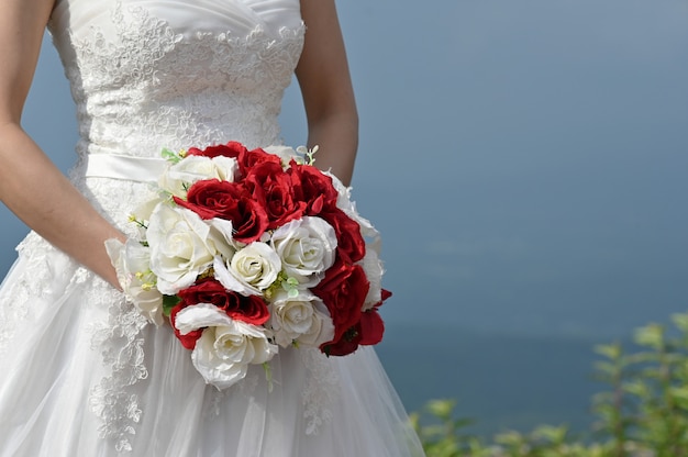 Geerntete Schussbraut, die einen Blumenverschluß auf vor Hochzeitsschuß hält