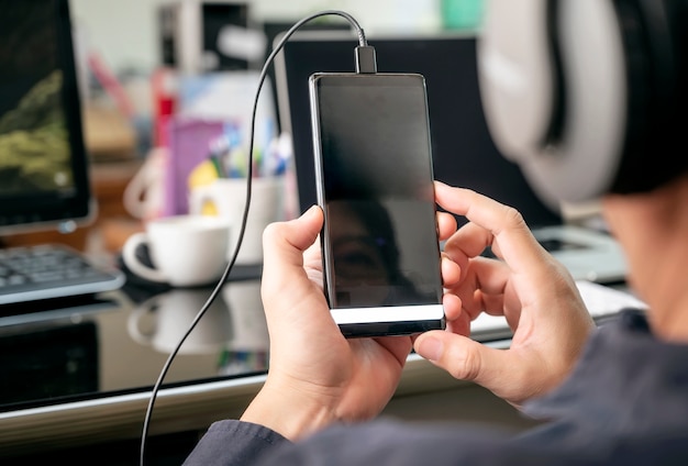 Geerntete Schussmannhand unter Verwendung des Smartphone beim Sitzen am Schreibtisch.