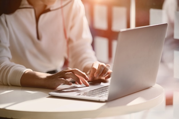 Geernteter Schuss der weiblichen Hand zu Hause schreibend auf ihrem Studioarbeitsplatz des Laptops