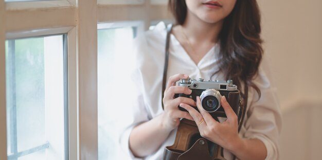 Geernteter Schuss des jungen professionellen weiblichen Fotografen, der Weinlesekamera hält