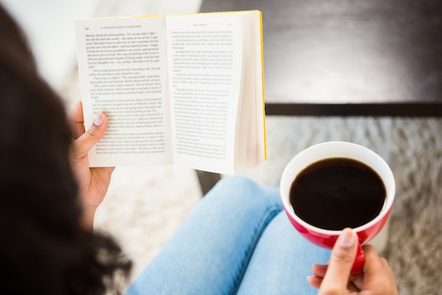 Geerntetes Bild der Frau mit Kaffeelesebuch