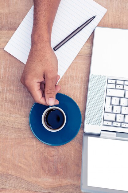 Geerntetes Bild des Geschäftsmannes Kaffee bei der Anwendung des Laptops auf Schreibtisch im Büro trinkend