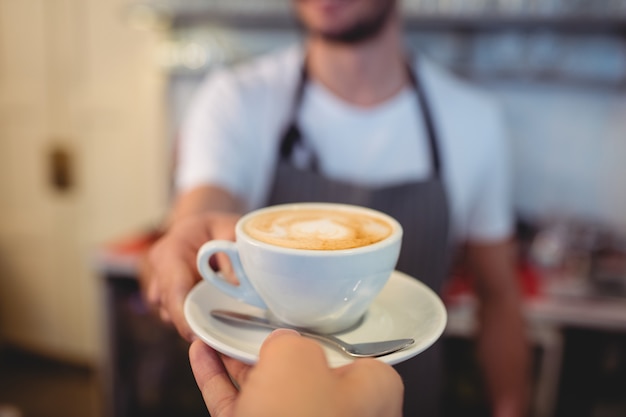 Geerntetes Bild des Kunden Kaffee vom Kellner am Café nehmend