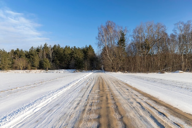 Gefährliche Straße im Winter, rutschige, schlammige Straße mit Spuren von Autos im Winter nach Schneefall