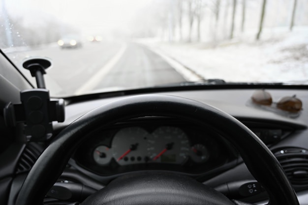 Gefährliche Wintersaison mit Schnee auf der Straße Der Innenraum des Autos aus Sicht des Fahrers gefährlicher Verkehr bei schlechtem Wetter