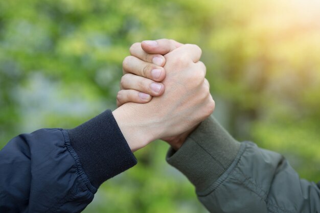 Gefährtenhand umklammert Erfolgsvertrauen, selbstbewusstes Konzept. oder Nahaufnahme einer Geschäftshand zwischen zwei Kollegen auf Parks.