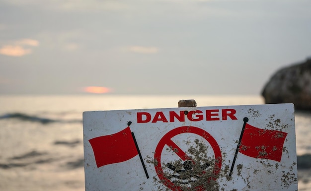 Gefahr nicht schwimmen Schild mit zwei roten Fahnen, verschwommenes Meer im Hintergrund