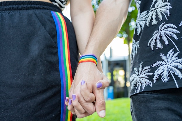 Gefaltete Hände auf natürlichem Hintergrund mit LGBT-Armband