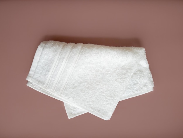 Gefaltetes Handtuch aus weißer Baumwolle auf beigem Hintergrund